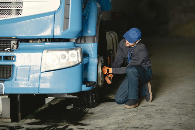 A mechanic repairing a truck wheel with IoT predictive maintenance technology in action.