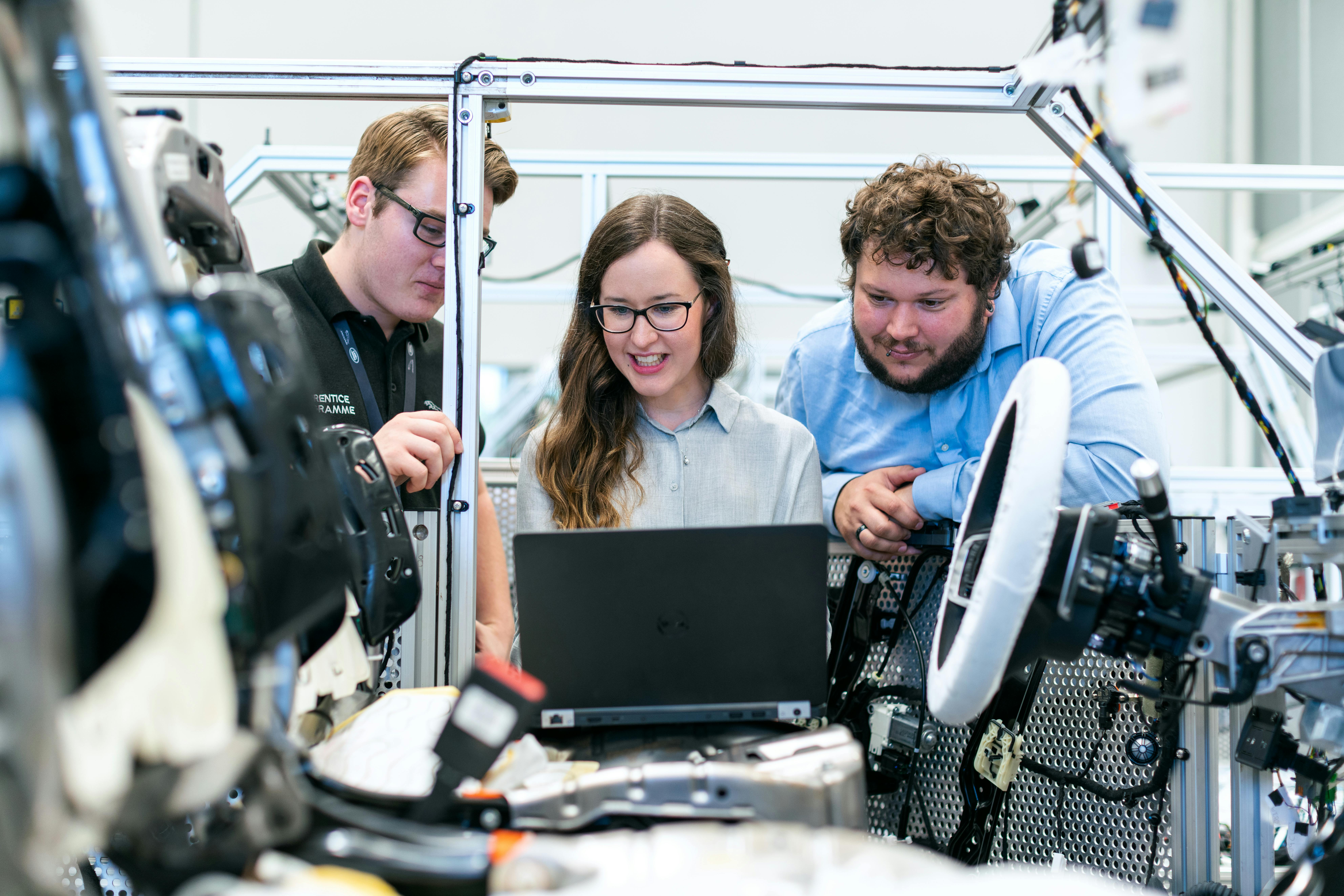 A group of software engineers collaborating and testing a new application on laptops in a modern office setting.